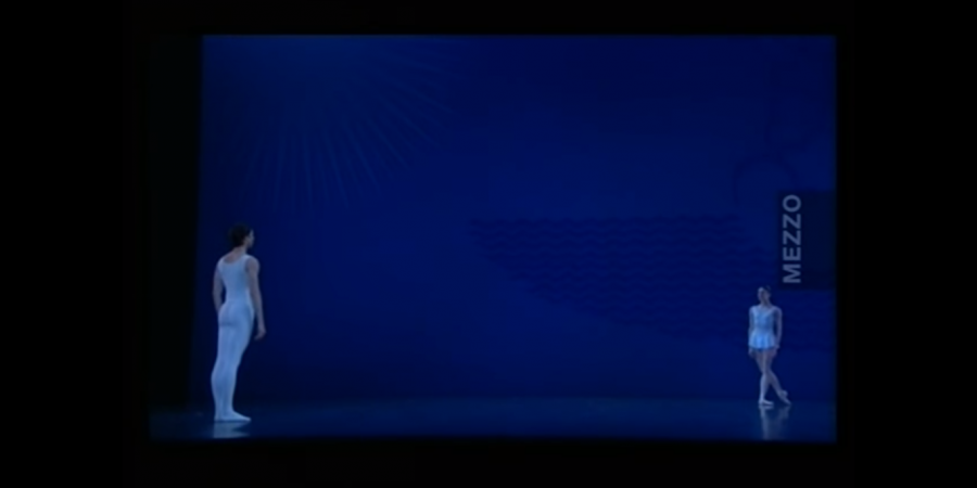 Um palco vazio com fundo azul. Um homem e uma mulher, vestidos de branco, acabaram de se defrontar